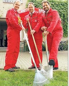 Günter Freitag, Bernhard Hadel und Guido van den Berg posieren beim Pressetermin in Arbeitskluft und Gartengeräten vor dem Fritz-Erler-Haus in Liblar