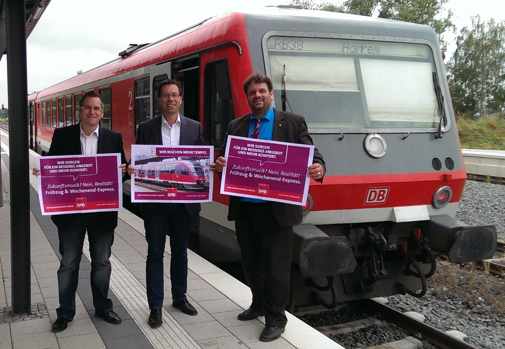 Sascha Solbach, Dierk Timm und Guido van den Berg MdL mit Plakaten der SPD-S-Bahn Kampagne auf dem Bedburger Bahnhof (2014)