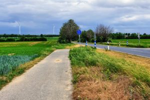 Kurzes Radwegfragment unter stürmischem Himmel an der K38